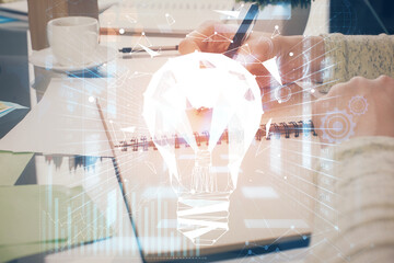 Bulb hologram over hands taking notes background. Concept of idea. Double exposure