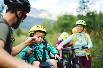 Family with tired small children cycling outdoors in summer nature.