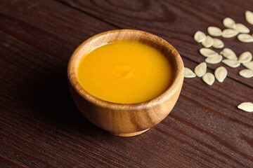 Pumpkin soup with pumpkin seeds on wooden table