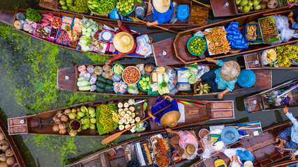 Fototapeta premium Aerial view famous floating market in Thailand, Damnoen Saduak floating market, Farmer go to sell organic products, fruits, vegetables and Thai cuisine, Tourists visiting by boat, Ratchaburi, Thailand