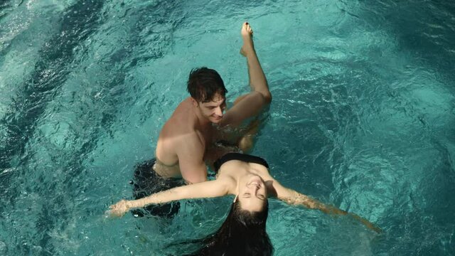 Happy couple having fun in pool. Happy man looking beautiful woman in spa.