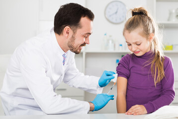 Fototapeta premium Young male doctor ready to make injection to teenage female visitor in hospital