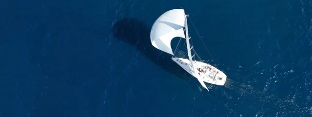 Gordijnen Aerial drone ultra wide panoramic photo of beautiful sailboat with white sails cruising deep blue sea near Mediterranean destination port © aerial-drone