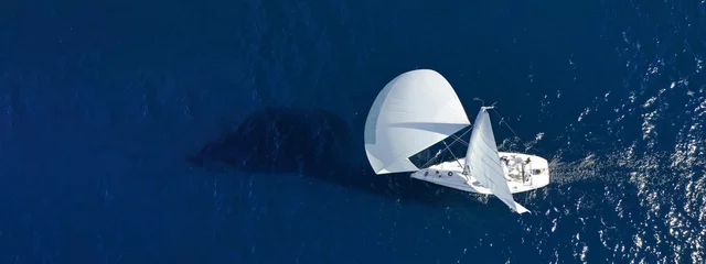 Fotobehang Aerial drone ultra wide panoramic photo with copy space of beautiful sailboat with white sails cruising deep blue sea near Mediterranean destination port © aerial-drone