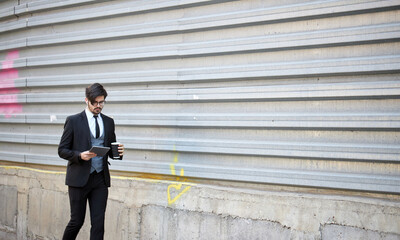 Businessman using a tablet pc outside on the city street wearing elegant clothes