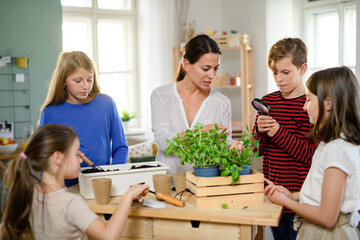 Group of homeschooling children with teacher planting herbs indoors, coronavirus concept.