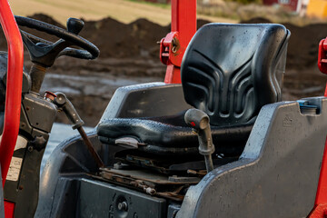 Cabin and drivers seat on a large excavation machine on a construction site.
