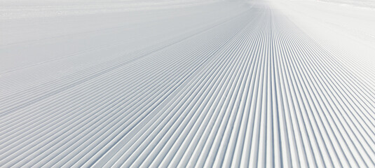 Close-up straight line rows of freshly prepared groomed ski slope piste. - obrazy, fototapety, plakaty