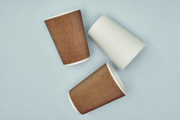 Paper cup in hand on a colored background. Eco-friendly materials in a coffee shop, biodegradable disposable tableware. Close up.