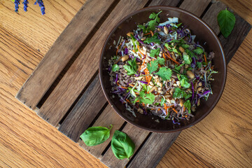 Asian beef salad with vegetables and nuts in a white bowl on a wood background Asian food concept