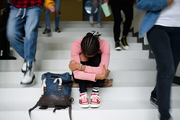 Depressed young student with face mask sitting on floor back at college or university, coronavirus concept.