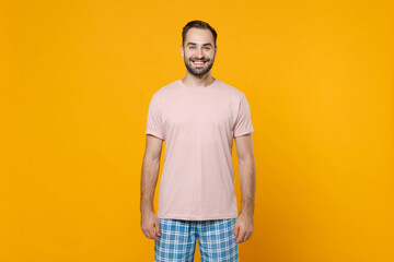 Smiling funny handsome young bearded man 20s in pajamas home wear looking camera while resting at...