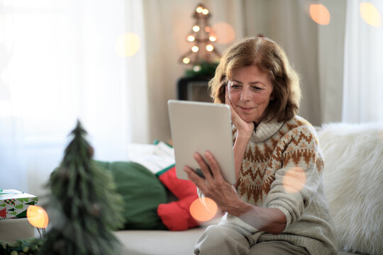 Senior Woman Indoors At Home At Christmas, Having Video Call With Family.