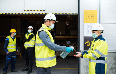 Group of workers with face mask in front of warehouse, coronavirus and disinfecting hands concept.