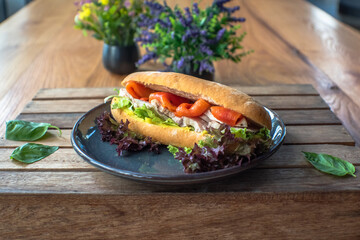 Chicken breast smoked salmon on rye bread sandwich on wooden table background