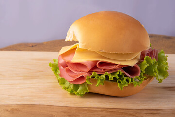 Mortadella, cheese and lettuce sandwiches, seen in detail on wooden surface, gray background, selective focus. © Milton Buzon