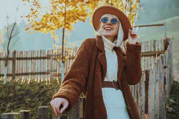 Outdoor autumn fashion, lifestyle portrait of smiling woman, model wearing trendy outfit with hat,...