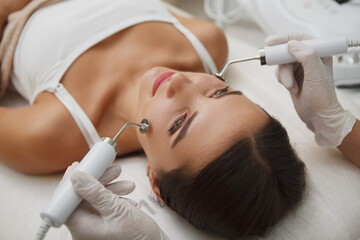 Close up of professional cosmetologist doing facial skincare treatment for her female client