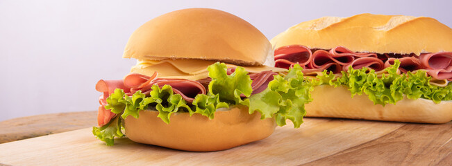 Mortadella, cheese and lettuce sandwiches on wooden surface, gray background, selective focus. © Milton Buzon