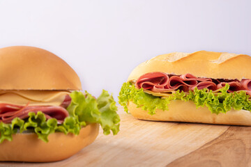 Mortadella, cheese and lettuce sandwiches on wooden surface, gray background, selective focus.