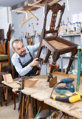 Professional furniture restorer inspecting vintage armchair in workshop