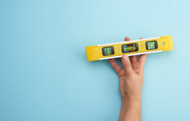 female hand hold plastic yellow level tool with capsules