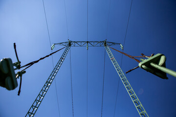 Construction of high voltage power transmission line. Behind is a clear blue sky.