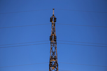 Symmetrical photography of the construction of the transmission line for the transmission of high voltage electricity. Behind is a clear blue sky.