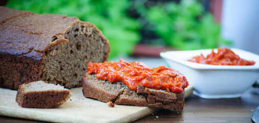 Homemade whole grain einkorn bread, a slice with Lutenitza and a cup with Lutenitza. Traditional bulgarian food.
  Close up picture