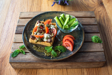 Delicious salted belgian waffles with sun dried tomatoes and kalamata olives on green plate