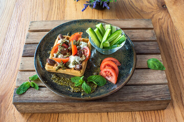 Delicious salted belgian waffles with sun dried tomatoes and kalamata olives on green plate