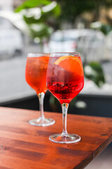 Two glasses if traditional Italian cocktail on a wooden table in an outdoor cafe