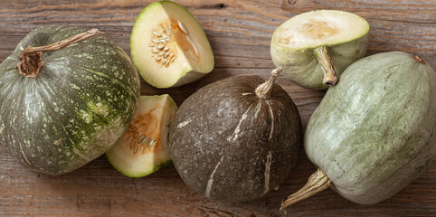 Pumpkins close up whole and cut top view on a wooden background. Autumn composition.