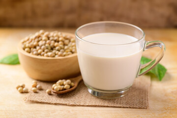Soy milk in the glass and soy beans on wooden background