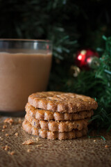 Winter holidays, New Year or Christmas concept. Composition of homemade cookies and glass of coffee on a wooden vintage table top on a blurred background of a Christmas tree and toys.