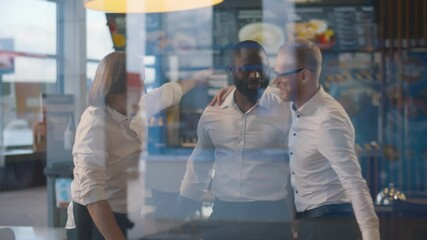 View through window of diverse cafeteria staff chatting and hugging before opening
