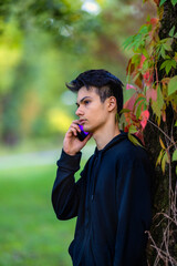 Fototapeta premium Young man with mobile phone in the autumn park