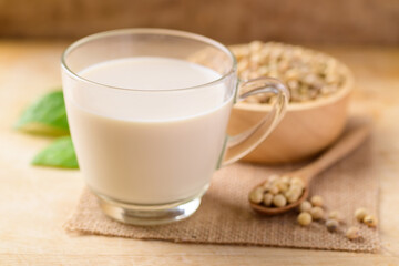 Soy milk in the glass and soy beans on wooden background