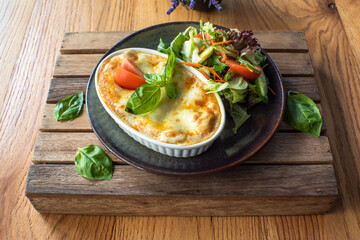 Traditional Italian lasagna with fresh salad vegetables, On a wooden try