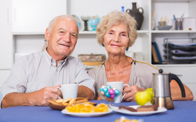 Happy senior couple enjoying conversation over cup of coffee at home