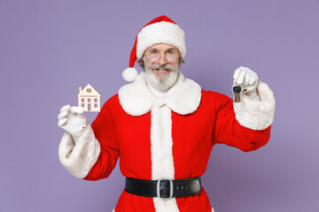 Fototapeta na wymiar Smiling Santa Claus man in Christmas hat red suit coat white gloves glasses holding house and bunch of apartment keys isolated on violet background. Happy New Year celebration merry holiday concept.