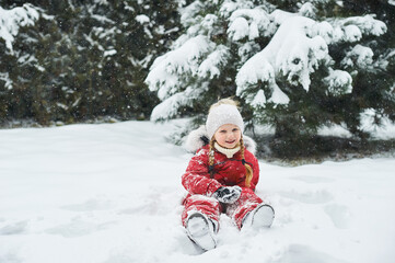 Fototapeta na wymiar portrait of a beautiful caucasian child on a background of snow-covered Christmas trees