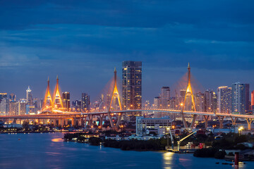 Fototapeta na wymiar Large suspension bridge over Chao Phraya river at twilight, with city in background