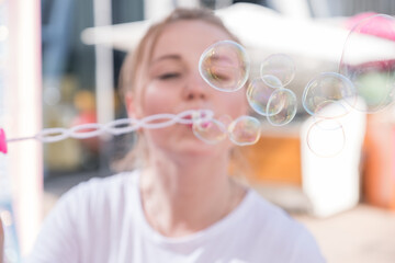 Cute cheerful woman blowing bubbles outdoors. Sunny portrait on a daylight.
