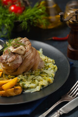 Boiled knuckle, served with cabbage and baked potatoes. Front view. Darkblue background. Dark mod.