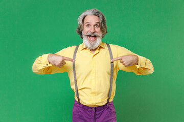 Surprised elderly gray-haired mustache bearded man wearing basic yellow shirt suspenders pointing...