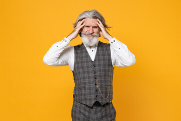 Displeased worried elderly gray-haired bearded business man in checkered suit waistcoat white shirt put hands on head isolated on yellow background studio portrait. Achievement career wealth concept.