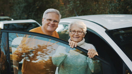 Senior couple purchased new car. Standing near the door and woman holding keys. High quality photo