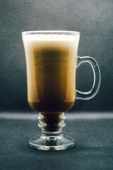 Creamy Irish coffee in a glass on black background. Shallow depth of field, blur, whiskey, drink, bokeh, Christmas.