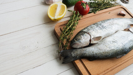 Seafood. Two raw rainbow trouts marinated with lime, pepper, spices and rosemary on wooden board. Healthy food and dieting concept.